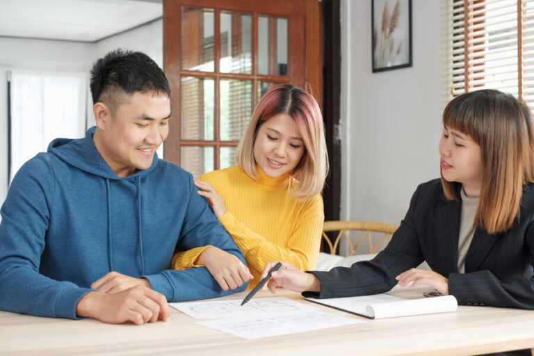 Un couple qui signe l'acte de vente de l'achat de la maison de leur parent