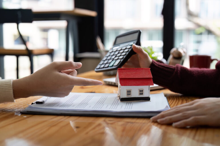Un agent immobilier montrant son tarif après l'avoir calculé sur une machine avec les contrats conclus sur la table