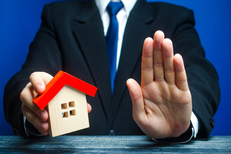Un agent immobilier qui n'est pas prête à vendre sa maison en tenant la clé et une petite maison dans sa main.