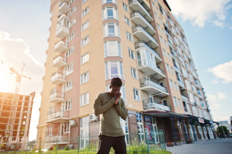 Un homme debout devant un appartement qu'il veut louer après avoir mis le sien en location