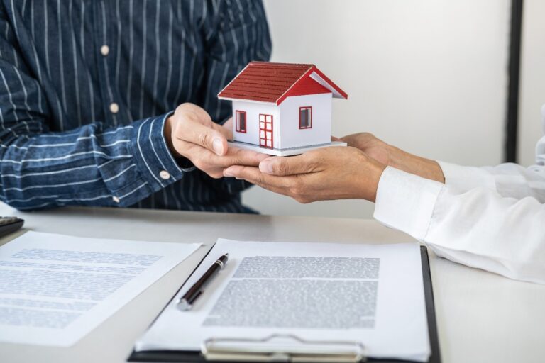 Des documents d’assurance habitation posés sur une table, avec clés du logement et stylo pour la signature