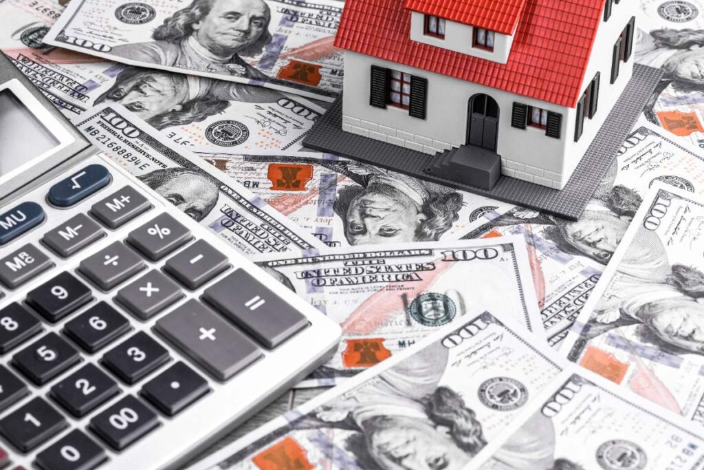 Une calculatrice, une maison et des monnaies sur une table