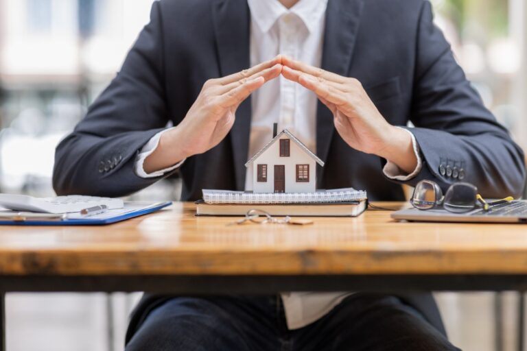 Un modèle de maison présenté par un agent immobilier qui est assis dans un bureau