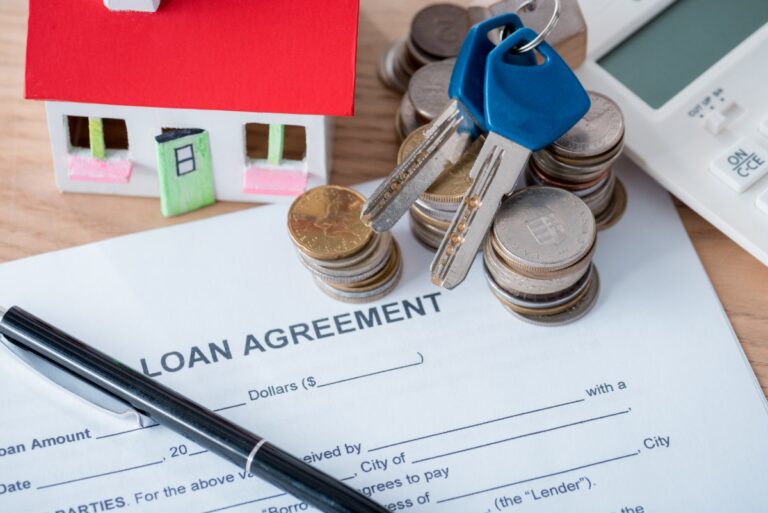 Un contrat de vente immobilier, un stylo, des monnaies et des argents