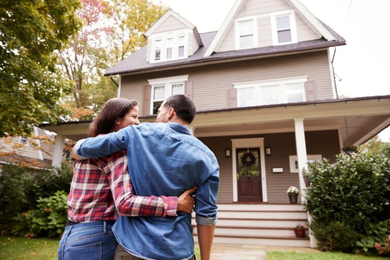Un couple qui se tient debout devant leur maison