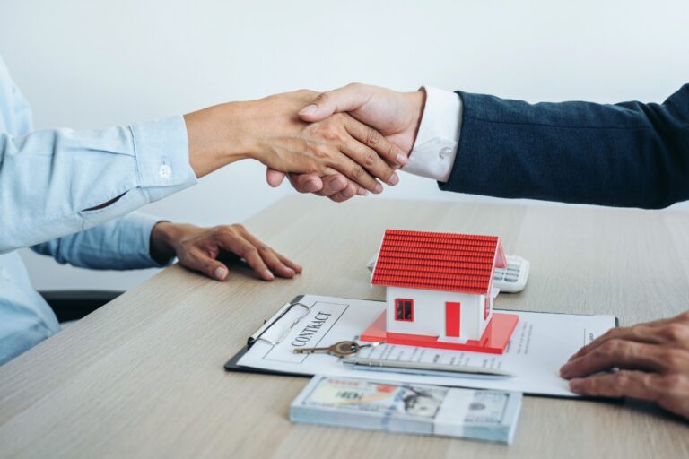 Un agent immobilier et un client qui se serrent les mains avec un contrat conclu