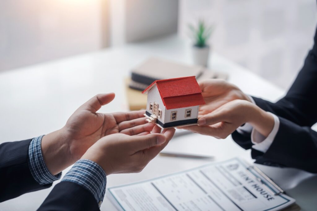 Un agent immobilier donnant une maquette de maison à une personne