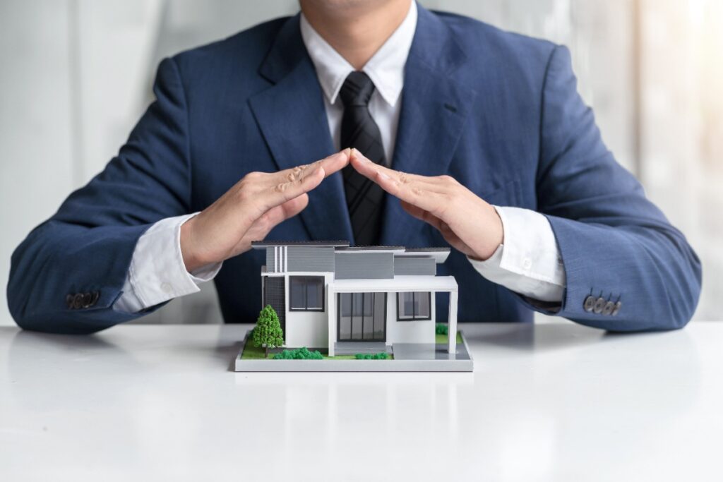 Un agent immobilier avec une petite maison sur la table