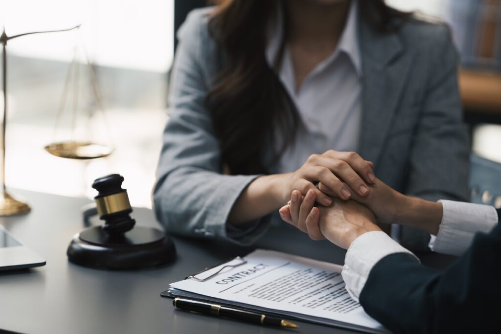Un juriste tenant la main d'une personne devant un contrat