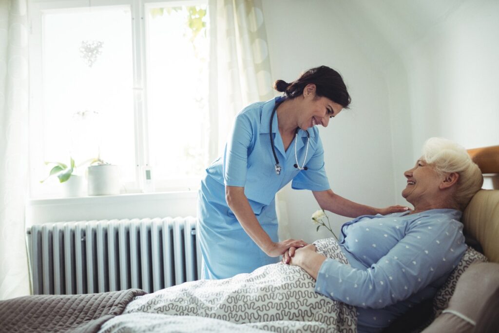 Une infirmière discutant avec une femme âgée allongée sur le lit
