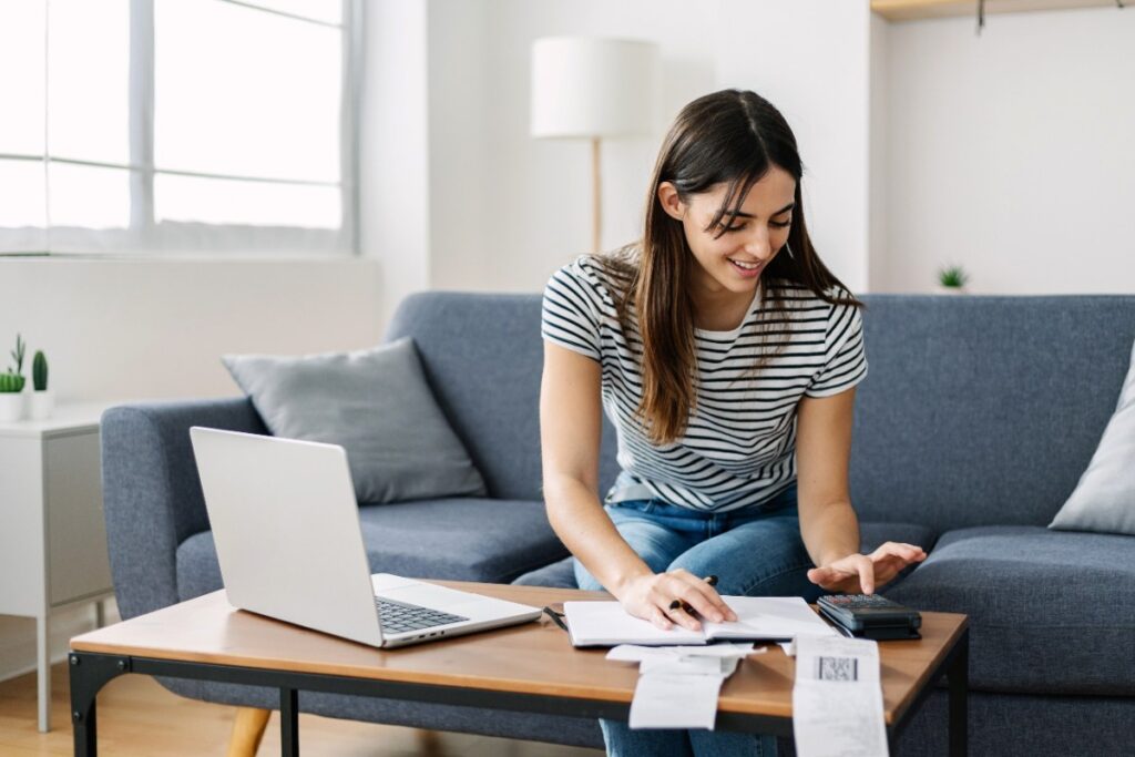 Une femme souriante calculant ses finances à la maison